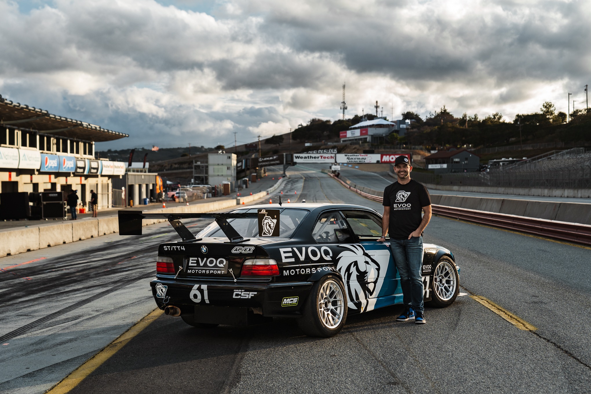 DJ Quint beside an EVOQ race car at Laguna Seca